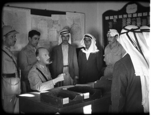 Arab Legion [men meeting around a table, some in Arab dress, others in military uniform] [picture] : [Jordan] / [Frank Hurley]