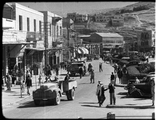 Transjordan Film Clips, Amman [busy street scene with trucks, cars, shops and people] [picture] : [Jordan] / [Frank Hurley]