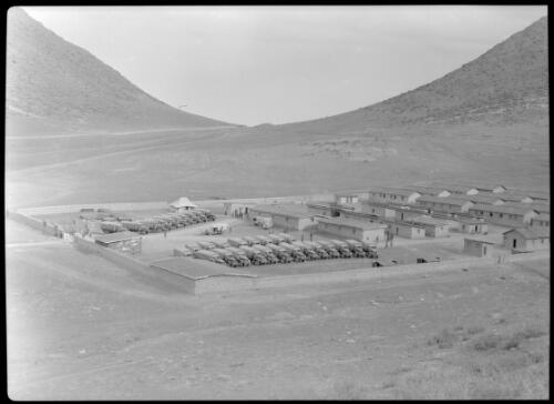 Road to Russia [overview of a walled in site with rows of trucks and buildings] [picture] : [Iran, World War II] / [Frank Hurley]