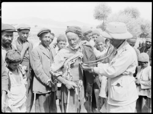 With the travelling dispensary Beisitun Kermanshah Persia [doctor using a stethoscope] [picture] : [Iran, World War II] / [Frank Hurley]