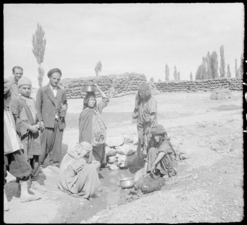 [Group of villagers, with dumps of winter fuel behind them, 1] [picture] : [Iran, World War II] / [Frank Hurley]