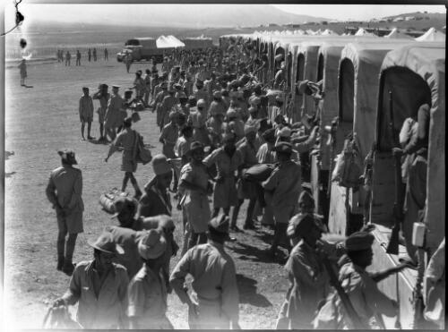 [Troops unloading supplies from the back of neatly aligned trucks] [picture] : [Iran, World War II] / [Frank Hurley]