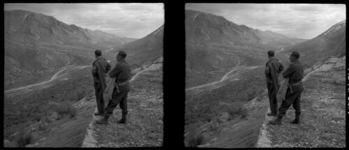 Rd to Russia, scenes around the Paitak Shah Passes. [two uniformed male figures overlooking a valley with buildings grouped next to the road that runs along the valley floor, World War II] [picture] : [Iran] / [Frank Hurley]