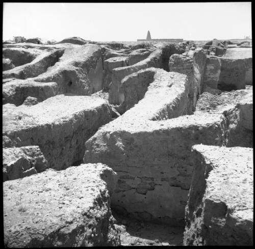 [Close-up of ruins, on the horizon a tall spiralled tower, enclosed by a stone wall, and a dome flanked by two columns, World War II] [picture] : [Iran] / [Frank Hurley]