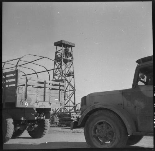Sunday shots, Iran [two trucks, the rear of one variously marked '9', '30', 'H5171247' and '1867', and a lookout tower, World War II] [picture] : [Iran] / [Frank Hurley]