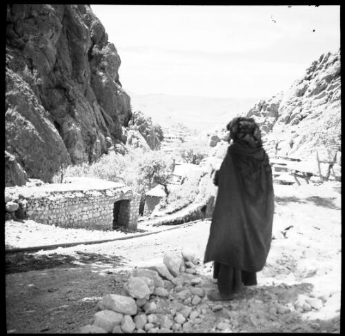 Sunday shots, Iran [figure facing a town of flat roofed buildings nestled amongst steep, rocky mountains, World War II] [picture] : [Iran] / [Frank Hurley]