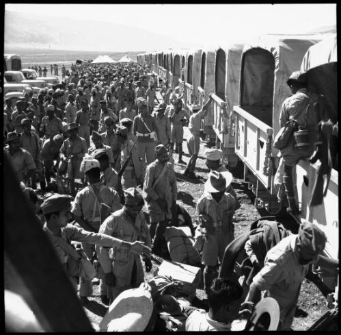 Sunday shots, Iran [troops unloading supplies from the back of neatly aligned trucks, World War II] [picture] : [Iran] / [Frank Hurley]