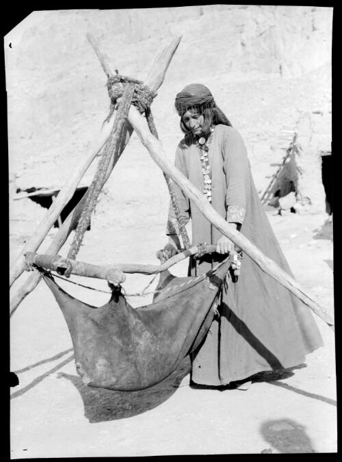 Woman of Beisitun working the goatskin churn, Persia [picture] : [Iran, World War II] / [Frank Hurley]