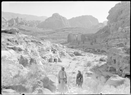 Petra valley [two figures in foreground, one in Arab military dress ca. 1940-1946] [picture] : [Petra Valley, Jordan] / [Frank Hurley]