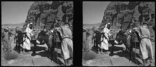 [Figures in Arab dress and donkeys in foreground, Petra monuments, including the Urn temple and the Palace behind ca. 1940-1946] [picture] : [Petra Valley, Jordan] / [Frank Hurley]