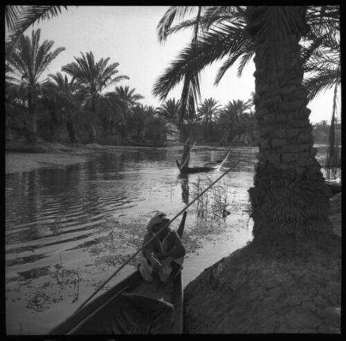[Waterway or river with palm trees and men in small boats wearing Arab dress ca. 1940-1946] [picture] : [Petra Valley, Jordan] / [Frank Hurley]