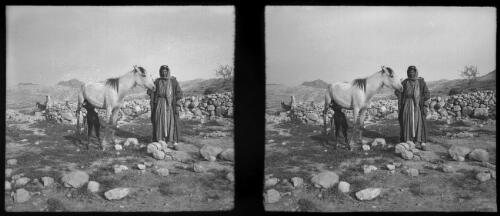 Wady Musa Petra [Man in Arab dress poses with horse and feeding foal ca. 1940-1946] [picture] : [Petra Valley, Jordan] / [Frank Hurley]