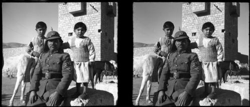 Glimpse in the valley of Petra, lying between the Dead Sea & the Gulf of Aquaba, stereo [portrait of a police sergeant with two children, police post behind ca. 1940-1946] [picture] : [Petra Valley, Jordan] / [Frank Hurley]