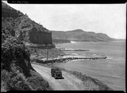 [A truck on a coastal road, cliffs and coastline in the background] [picture] / [Frank Hurley]