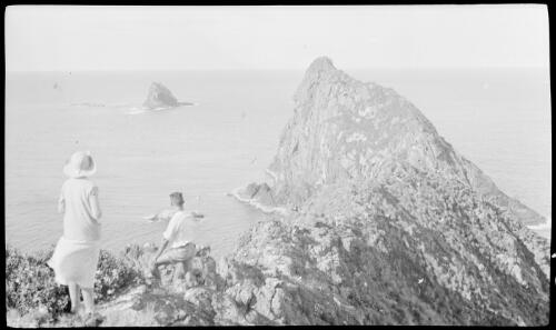 [Unidentified woman and man standing on a ridge looking at a nearby island, Lord Howe Island] [picture] / [Frank Hurley]
