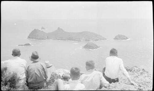 [Six unidentified people sitting on a cliff looking at Roach Island, Lord Howe Island] [picture] / [Frank Hurley]