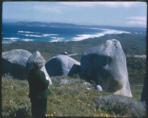 [Unidentified woman standing amongst large rocks with beach in background, Western Australia] [transparency] / [Frank Hurley]