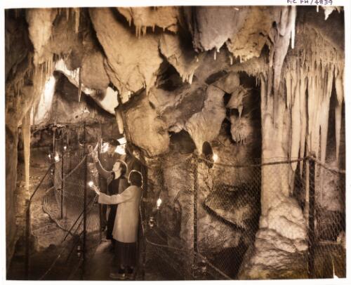 [Visitors to the Right Imperial Cave inspecting the  Sentinel with the Grand Stalactites behind them] [transparency] / [Frank Hurley]