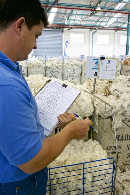Man standing next to bales of fine merino wool on sale at an auction, Sydney, approximately 2009 / Robin Smith