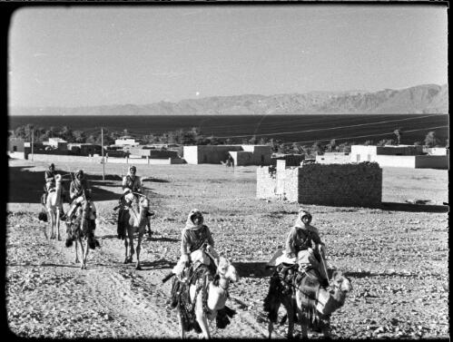Aquaba, Jordan [soldiers with Arab headdress riding camels, town behind] : [Trans-Jordan, World War II] [picture] / [Frank Hurley]