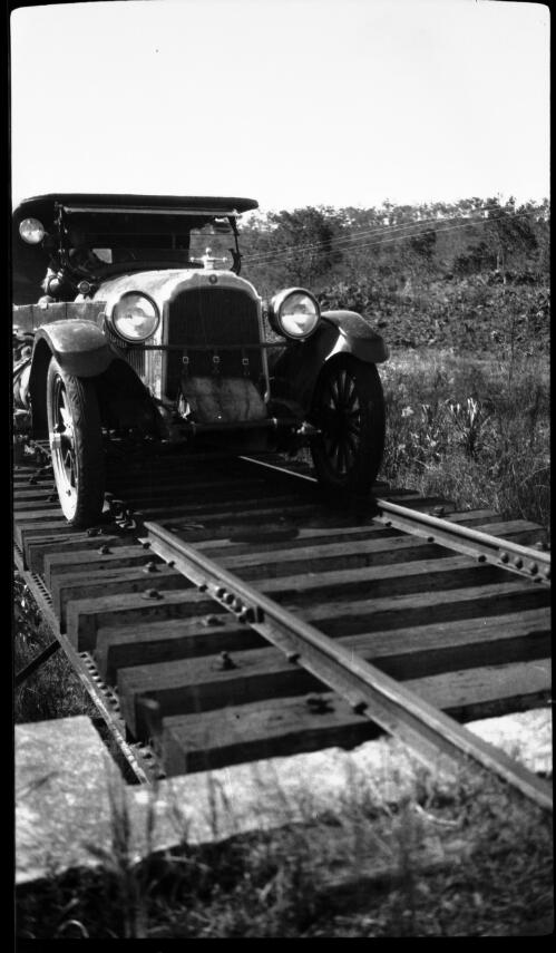 Crossing flooded country between Pine Creek and Darwin, June 1925 [motor vehicle on railway track, 2] [picture] : [Central Australia] / [Frank Hurley]
