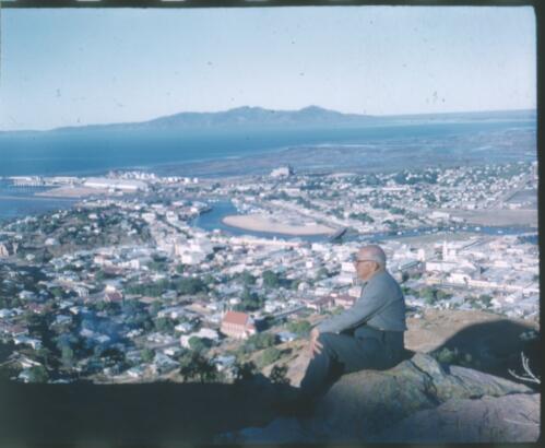 [Unidentified man sitting on rock looking over Castle Hill, Townsville?] [transparency] / [Frank Hurley]
