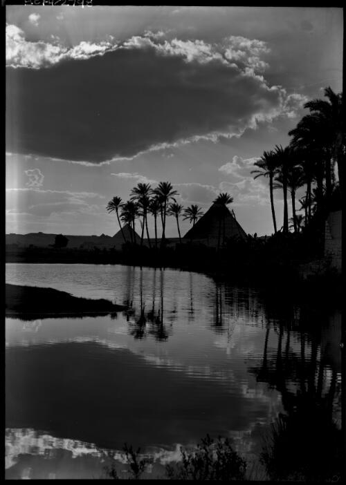[Pyramids at sunset, trees reflected in water] [picture] : [Cairo, Egypt, World War II] / [Frank Hurley]