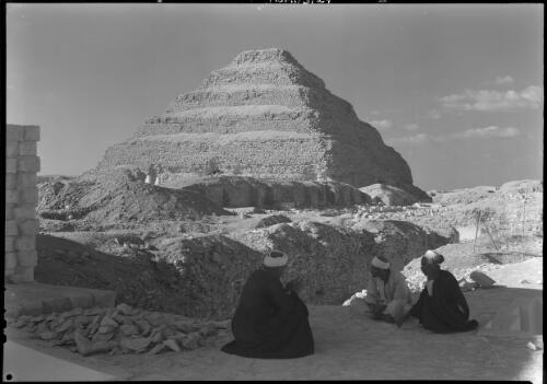 [Three men in robes sitting in front of the Step Pyramid of Djoser] [picture] : [Egypt, World War II] / [Frank Hurley]