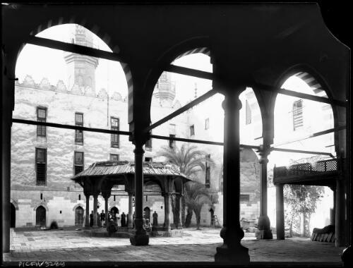 [A courtyard in a mosque with a central shelter and figures sitting on the walls, 1] [picture] / [Frank Hurley]