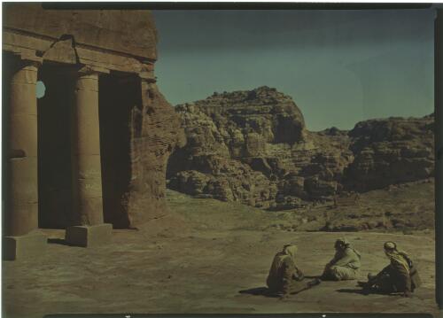 [Three seated figures, including two soldiers, beside ancient monument at Petra] [picture] : [Jordan, World War II] / [Frank Hurley]