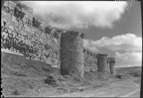 [Exterior wall of the Crac des Chevaliers, several people are at the top of the wall] [picture] : [World War II] / [Frank Hurley]