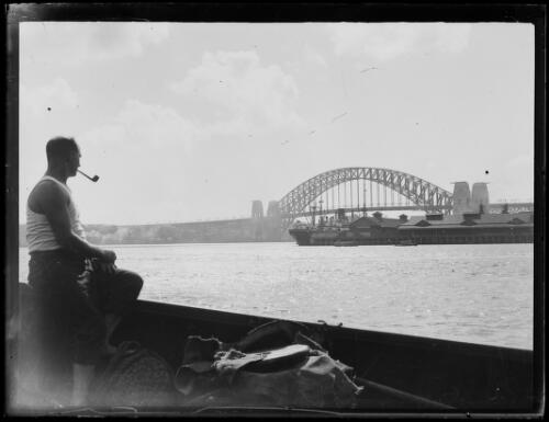 Man smoking a pipe looking towards the Sydney Harbour Bridge, Sydney, ca. 1935 [picture]