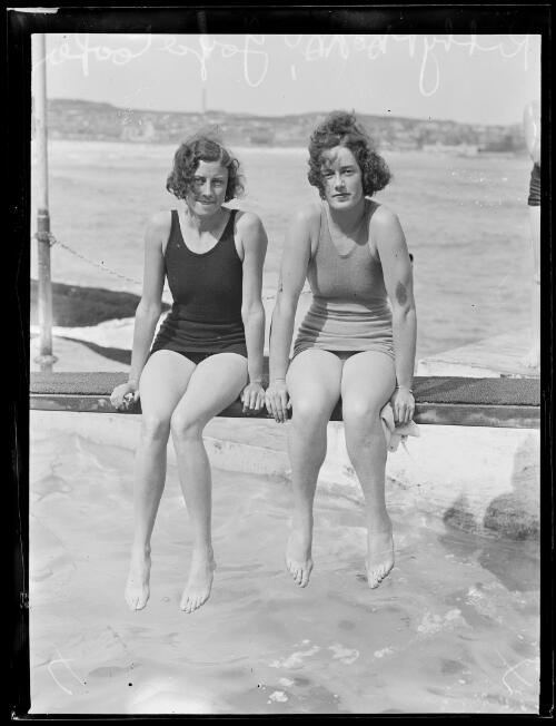 Australian swimmer Kitty Mackay and English swimmer Joyce Cooper sitting by the water in their bathing suits, New South Wales, 8 January 1934 [picture]