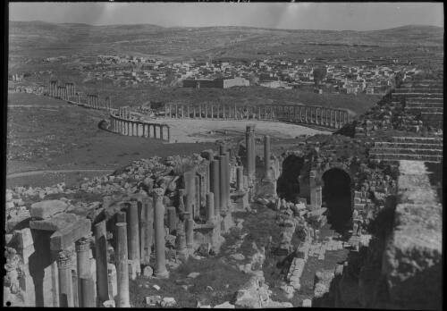 [Ancient ruin shot from a high vantage point, in the middleground is an amphitheatre with a town behind] [picture] : [Barqah, Libya] / [Frank Hurley]