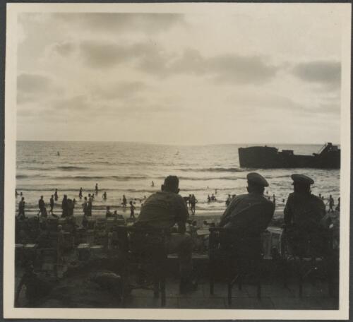 [Three seated military figures overlooking Tel Aviv beach, ship in outlying waters, 2] [picture] / [Frank Hurley]