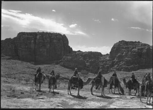 [Eight camels and riders in Petra landscape] [picture] : [Petra Valley, Jordan] / [Frank Hurley]