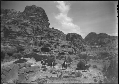 [Group of men on camels passing through Petra landscape] [picture] : [Petra Valley, Jordan] / [Frank Hurley]