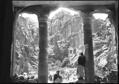 [Man with headdress looking out from the portico of the Farasa triclinium (hall for religious feasts), 2] [picture] : [Petra Valley, Jordan] / [Frank Hurley]