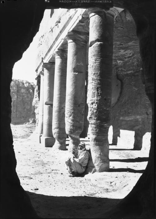 In Court of King's Urn Temple Petra [man with pipe resting against column] [picture] : [Petra Valley, Jordan] / [Frank Hurley]