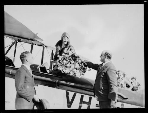 Aviatrix Irene Williams getting into her plane holding flowers on her flight from Perth to Sydney, Adelaide, 23 April 1932 [picture]