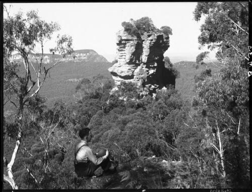 Orphan Rock in close up (Frank sitting in foreground) [picture] : [Blue Mountains, New South Wales] / [Frank Hurley]