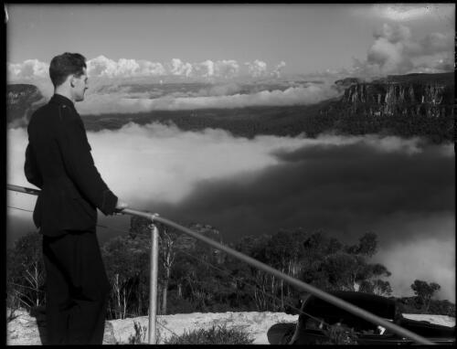 Chauffeur looking on Jamieson from above cliff drive, mists in valley [picture] : [Blue Mountains, New South Wales] / [Frank Hurley]