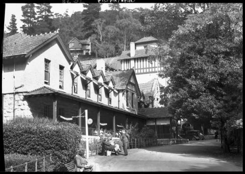 Caves House [close-up view, with some people sitting outside] [picture] : [Jenolan Caves, New South Wales] / [Frank Hurley]