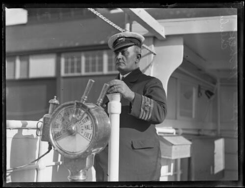 Captain Fisher of the S.S. Calula standing next to the wheel on the bridge, New South Wales, ca 1920s, 2 [picture]