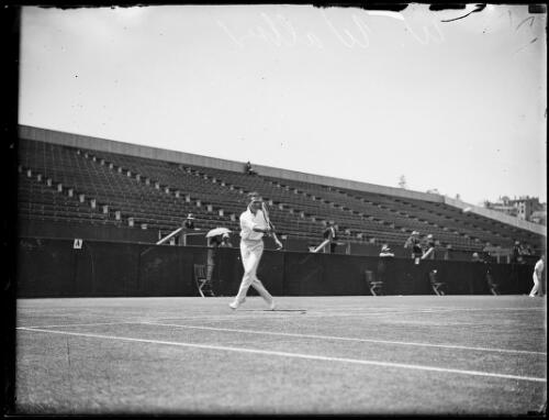 Tennis player W.B. Walker running to hit a forehand shot in an empty tennis stadium, New South Wales, ca. 1930s [picture]