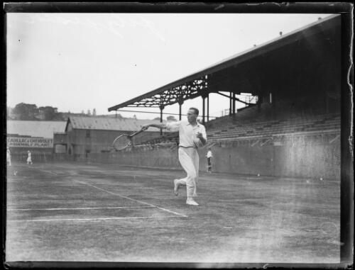 Tennis player Paul Fitzgerald hitting a backhand shot in an empty stadium, New South Wales, ca. 1920s [picture]