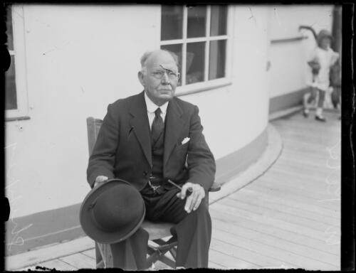 Captain W. Peters sitting on the deck of a boat holding a hat and pipe, New South Wales, ca. 1928 [picture]