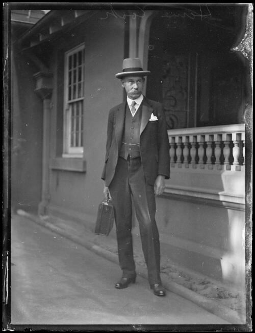 Politician James Newton Haxton Hume Cook holding a briefcase outside Parliament House, New South Wales, ca. 1930s [picture]