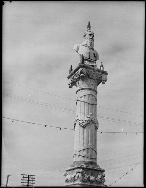 [Monument adorned with beer bottles, Port Douglas, Queensland, April 1957] [picture] / [Frank Hurley]