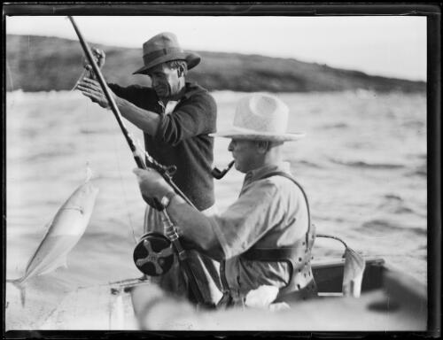 Two fishermen reeling in a catch in a boat, New South Wales, ca. 1934 [picture]